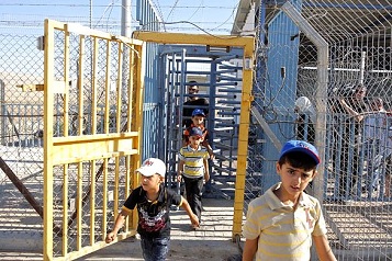 Palestinian children passing through an Israeli cattle steel gate